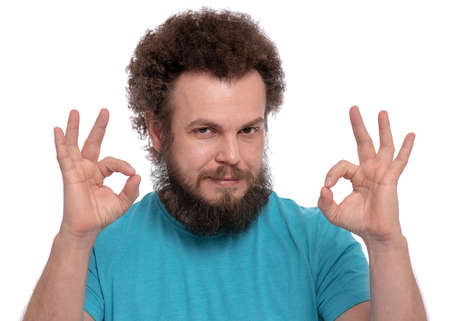 Portrait of bearded man with funny Curly Hair making Ok gesture, isolated on white background. Happy male smiling and showing okay sign. Caucasian man looking at camera.の写真素材