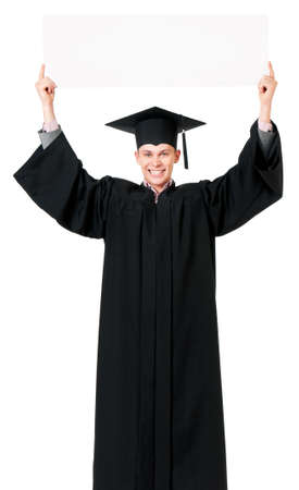 Happy male graduate student with a blank panel, isolated on white background. Handsome graduate guy student in mantle showing empty placard board.の写真素材