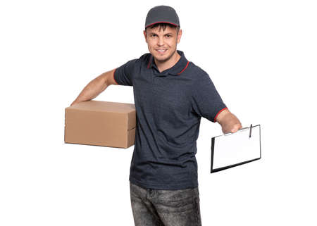 Portrait of Delivery man in cap holding cardboard box and clipboard with papers document. Handsome man, looking on camera. Courier isolated on white background.の写真素材