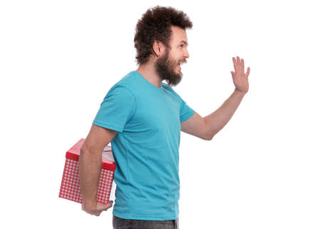 Crazy bearded Man with funny Curly Hair, isolated on white background. Happy guy holding behind the back gift box. Holidays concept.の写真素材