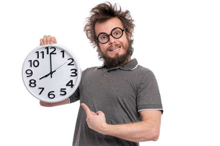 Crazy bearded Man with funny Haircut in eye Glasses holding Big Clock, isolated on white background. Time concept.の写真素材