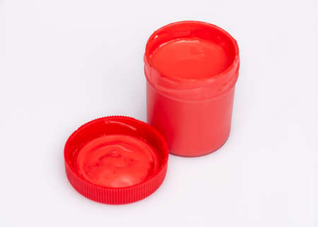 Opened red Gouache jar, on white background with copy space. Cans of different colors gouache paints.の写真素材