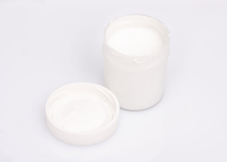 Opened white Gouache jar, on white background with copy space. Cans of different colors gouache...