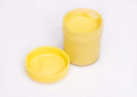 Opened yellow Gouache jar, on white background with copy space. Cans of different colors gouache paints.の写真素材