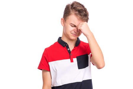 Portrait of tired teen boy touching his head suffering headache. Unhappy beautiful caucasian young teenager suffering from headache. Sad teenager isolated on white background.の写真素材
