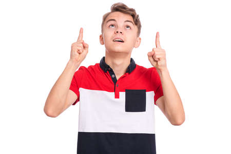 Portrait of surprised teen boy pointing fingers up at copy space, isolated on white background. Teenager pointing finger at something. Cute curious child looking away.の写真素材