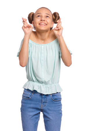 Portrait of teen girl crossing her fingers and wishing for good luck, isolated on white background. Caucasian teenager praying with crossed fingers, looking up. Child face expression emotions.の写真素材