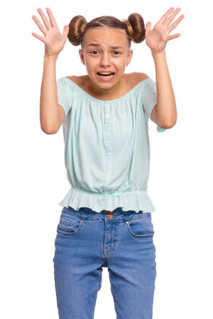 Portrait of surprised or shocked teen girl, isolated on white background. Scared child looking at camera in amazement. Upset caucasian teenager with raised hands.の写真素材
