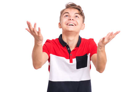 Portrait of teen boy raised hands and trying to catch something. Cute caucasian young teenager looking up, isolated on white background. Joyful child having fun.の写真素材