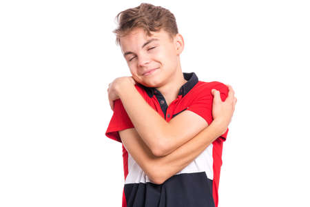 Self love and self care. Portrait of teen boy Hugging oneself, isolated on white background. Happy funny child. Cute caucasian young teenager smiling with eyes closed.の写真素材