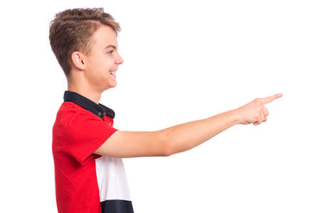 Portrait of teen boy pointing finger away at copyspace - side view, isolated on white background. Happy teenager smiling and pointing fingers at something. Cute child looking away - profile.の写真素材