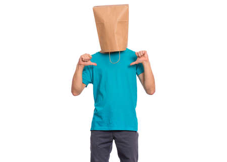 Portrait of teen boy with paper bag over head making thumbs up gesture. Teenager cover head with bag pointing thumbs on himself. Child pulling paper bag over head isolated on white background.の写真素材