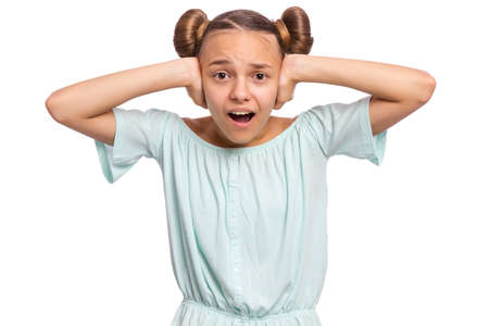Portrait of amazed teen girl covers ears with her hands. Child looking at camera. Caucasian young teenager, isolated on white background. Hear no evil concept.の写真素材