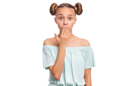 Portrait of surprised teen girl, isolated on white background. Funny child looks at camera in amazement, touching face with hands, covering mouth. Beautiful caucasian teenager, opens eyes with shock.の写真素材