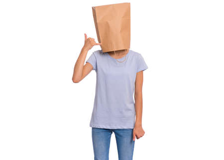 Portrait of teen girl with paper bag over head gesturing with fingers call me, isolated on white background. Child posing in studio showing sign with hand shaped like phone.の写真素材