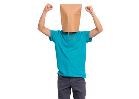 Portrait of teen boy with paper bag over head showing winning gesture. Successful and celebrating victory, triumphant child making win sign. Teenager cover head with bag, isolated on white backgroundの写真素材