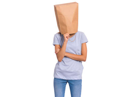 Pensive teen girl with paper bag over head. Thoughtful teenager cover head with bag holding hand near face isolated on white background. Child pulling paper bag over head.の写真素材