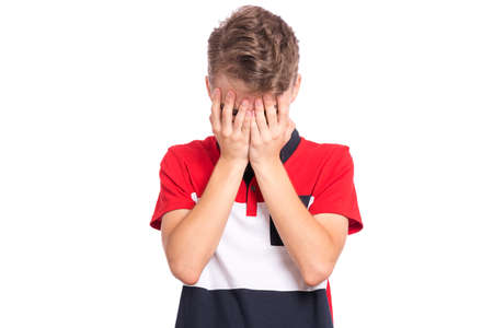 Portrait of teen boy with sad expression covering face with hands while crying. Upset caucasian young teenager, isolated on white background. Unhappy child crying, not showing his tears.の写真素材
