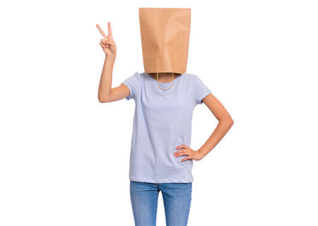Portrait of teen girl with paper bag over head making Victory gesture. Teenager showing victory sign isolated on white background. Happy child posing in studio.の写真素材