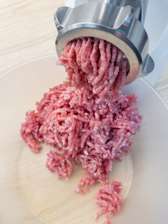 Meat grinder. Making homemade raw minced meat at kitchen. Close up of fatty pork minced.