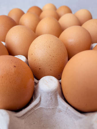 Brown eggs in cardboard egg box. Top view of raw organic chicken eggs in carton.の写真素材