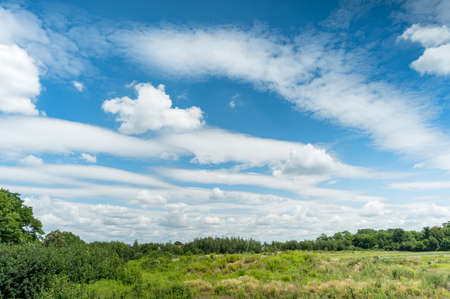 White fluffy clouds in blue sky background in green countryside at summerの写真素材