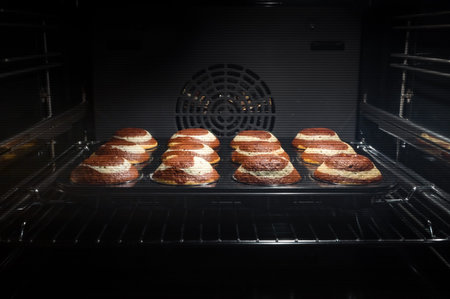 Baking process of chocolate muffins in oven, home made. Sweet cupcakes with cocoa baked in oven.の写真素材