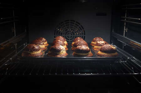 Baking process of chocolate muffins in oven, home made. Sweet cupcakes with cocoa baked in oven.の写真素材