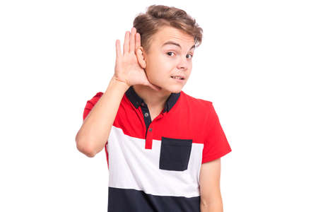 Teen boy with hand over ear listening an hearing to gossip. Closeup portrait teenager holds his hand near ear and listens carefully, isolated on whiteの写真素材