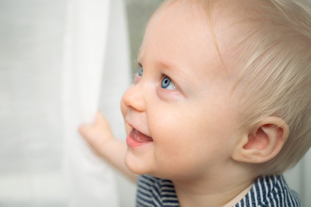 Cute baby with blue eyes - closeup portrait. Little boy at home looking away.の写真素材