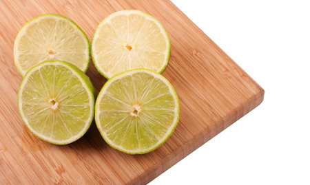 Slices of lemons and limes stacked on top of wood cutting boardの写真素材