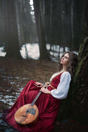 girl in an old dress with a guitar in the woodsの写真素材