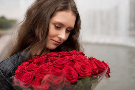 brunette girl with a bouquet of red roses close-upの写真素材