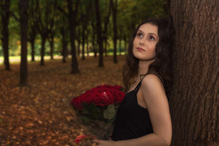 brunette girl with a bouquet of red roses close-upの写真素材