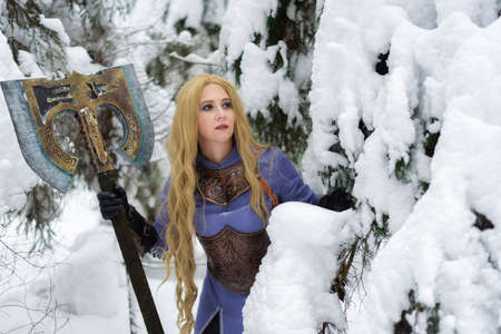warrior girl with blond hair and big ax in winter forestの写真素材