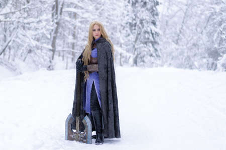 warrior girl with blond hair and big ax in winter forestの写真素材