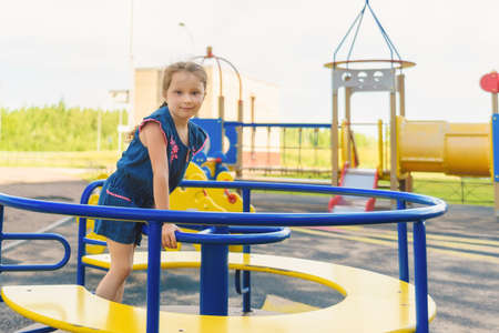 A cute young girl riding a chain carousel swing. Girl puts her hand like a plane's wings.の写真素材