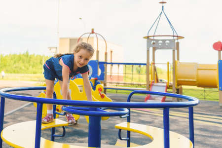 A cute young girl riding a chain carousel swing. Girl puts her hand like a plane's wings.の写真素材