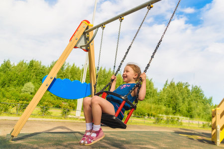 summer activity. Small kid playing in summer. Happy laughing child girl on swing. childhood daydream .teen freedom. romantic little girl on the swing, sweet dreams. Playground in park.のeditorial素材