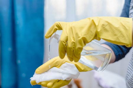 Close up of hands in rubber protective yellow gloves cleaning the white surface with a rag. Home, housekeeping conceptの写真素材