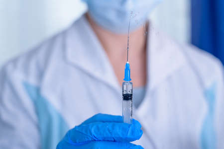 Doctor, nurse, scientist hand in blue gloves holding flu, measles,  vaccine disease preparing for child, baby, adult, man and woman vaccination shot, medicine and drug concept.の写真素材