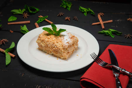 Homemade cake Napoleon with mint, decorated with cinnamon. On a white plate. On black backgroundの写真素材