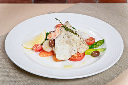 Warm salad with asparagus, prawns and codfish fillet. on a white plate. close-up viewの写真素材