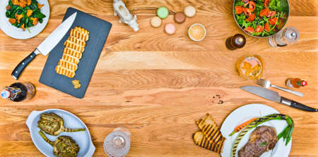 Top view of a beef steak and grilled cheese on a wooden table. salad with arugula. Grilled artichokes. Empty middleの写真素材