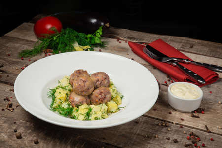 Homemade veal cutlets with mashed potatoes and fresh herbs. Served with tomato . On a beautiful wooden backgroundの写真素材