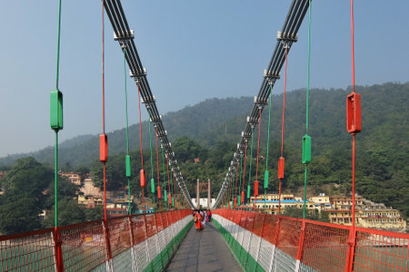 Rishikesh, India - November, 7th, 2017. Bridge over Ganga river, Ram Jhula, Rishikesh. People crossing Ram Jhula bridge.のeditorial素材