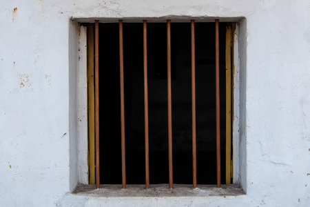 White wall with square window and vertical barsの写真素材