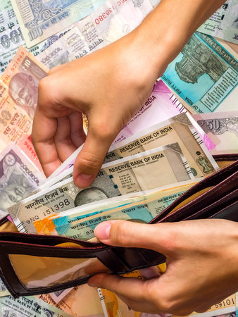 Woman's hands holding wallet with indian notes. 10, 20, 50, 100, 200, 500 and 2000 Indian rupees,...