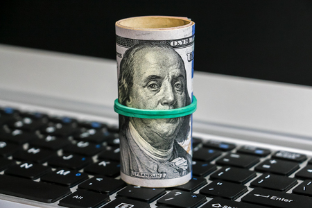 Closeup view of one hundred dollar banknotes lying on the laptop keyboard.の写真素材