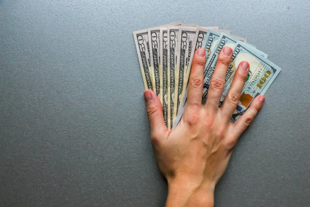 Closeup view of hand over one hundred and fifty dollar banknotes.